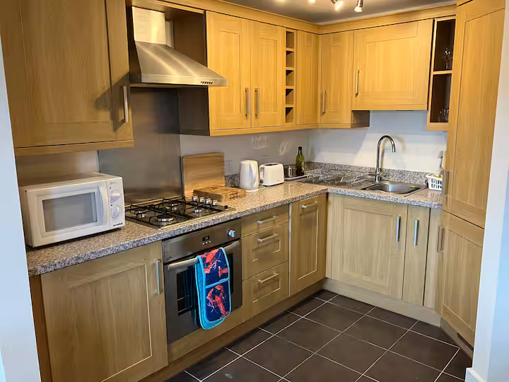 Fully equipped kitchen with oak cabinetry, gas hob, oven, microwave, kettle and toaster.